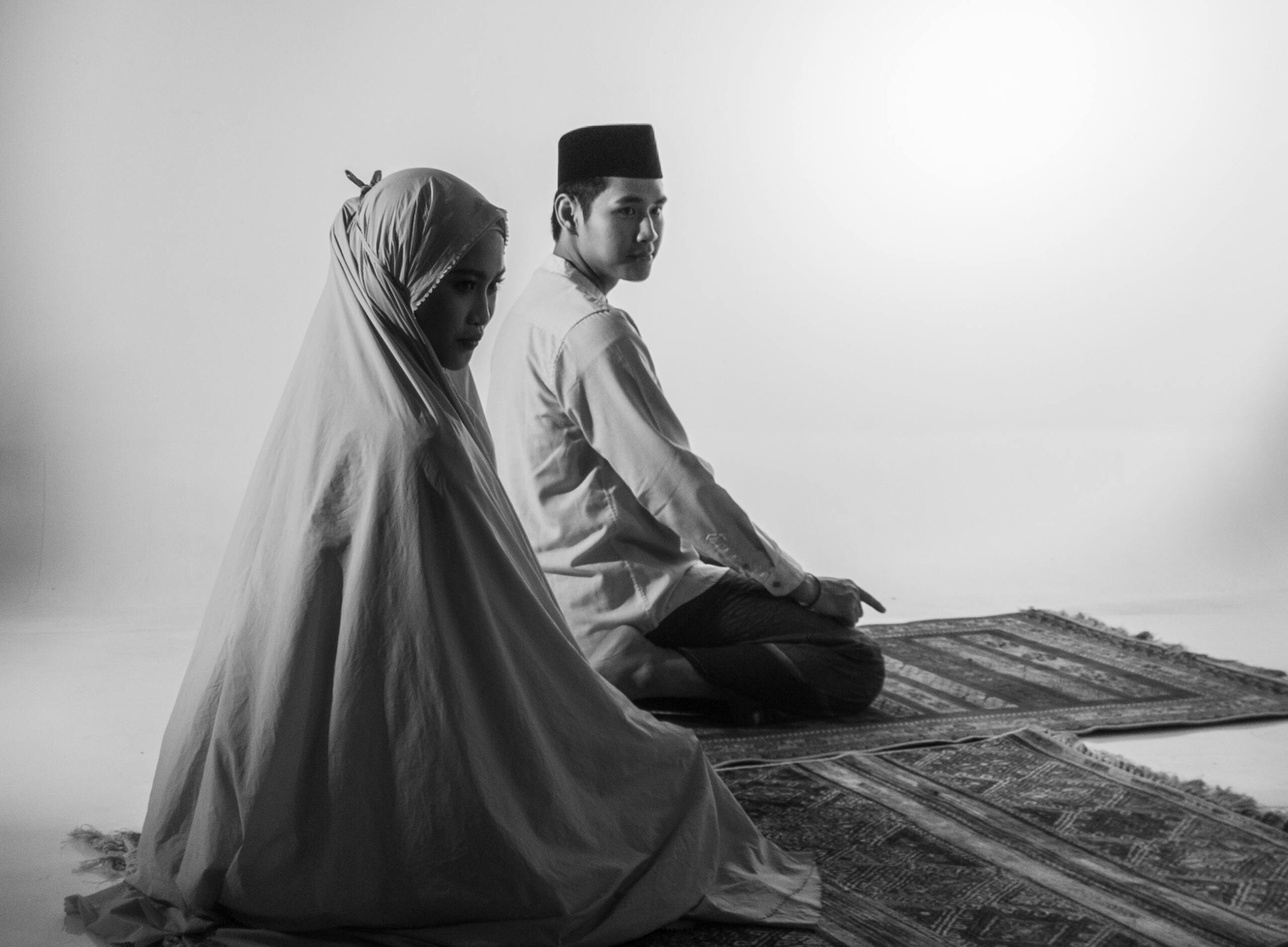A Muslim couple in traditional attire praying together indoors, symbolizing faith and devotion.